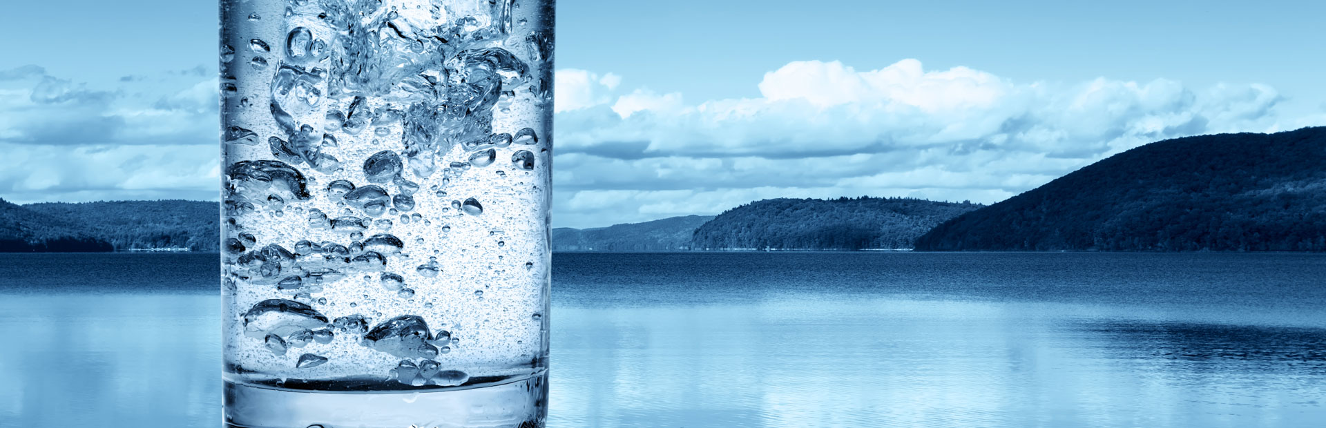 Glas Trinkwasser vor See und Bergen